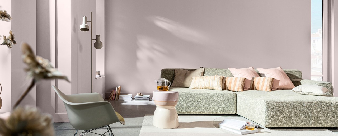 Wohnzimmer mit sanften, rosafarbenen Wänden und grauem Sofa